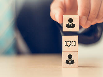 wooden blocks with handshake and suited silhouettes